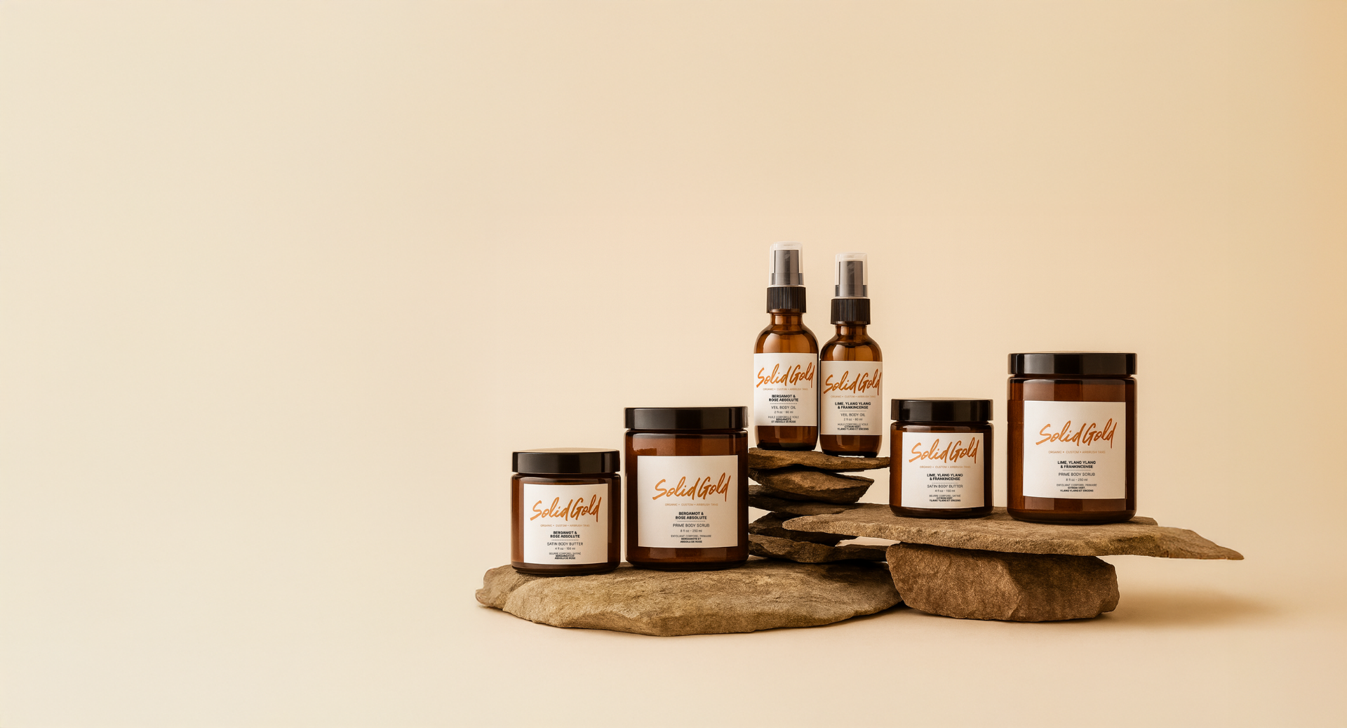 Solid Gold Ritual — Prime Body Scrub, Satin Whipped Body Butter, and Veil Body Oil on natural stone.