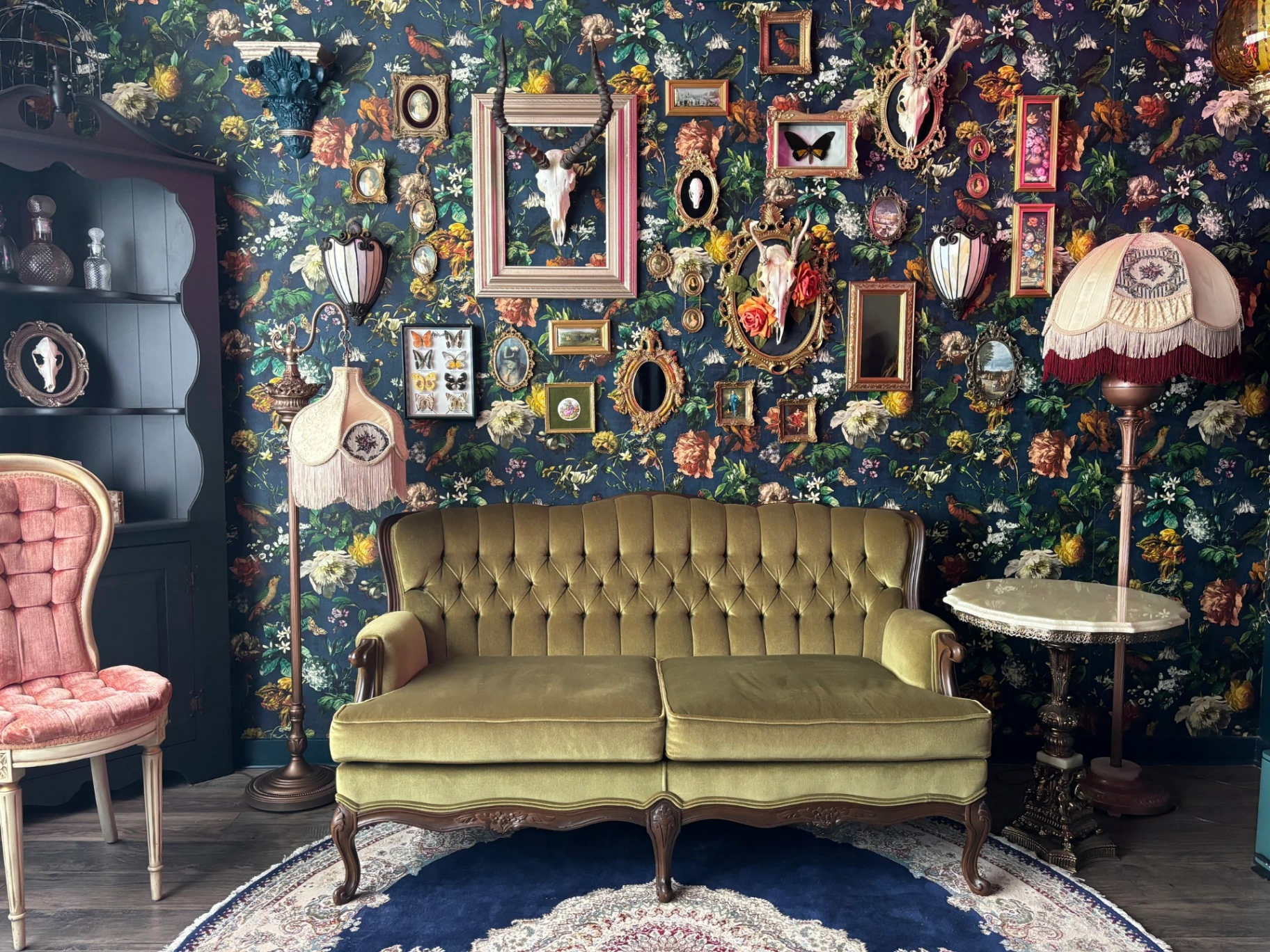 Glitterbox Studio — vintage olive sofa framed by a maximalist floral gallery wall.
