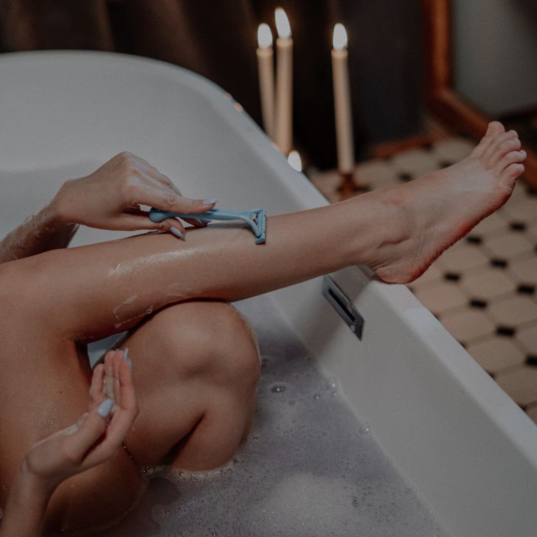 Shaving legs in a candlelit bath before a spray tan